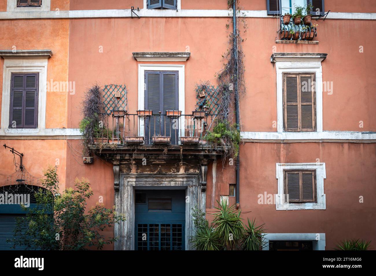 Facciata di un edificio in Italia con persiane attaccate a finestre e fioriere appese a un balcone Foto Stock