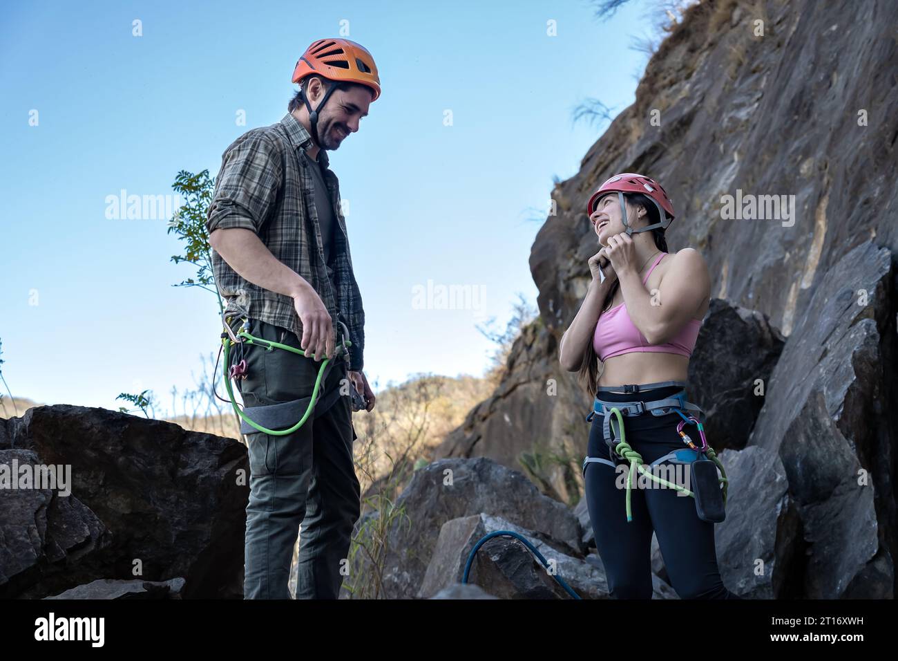 Ritratto di una giovane coppia ben equipaggiata con equipaggiamento di sicurezza in piedi insieme davanti alla montagna rocciosa. Squadra di arrampicatori. Foto Stock Ritratto di una giovane coppia ben equipaggiata con equipaggiamento di sicurezza in piedi insieme davanti alla montagna rocciosa. Squadra di arrampicatori. Foto Stock