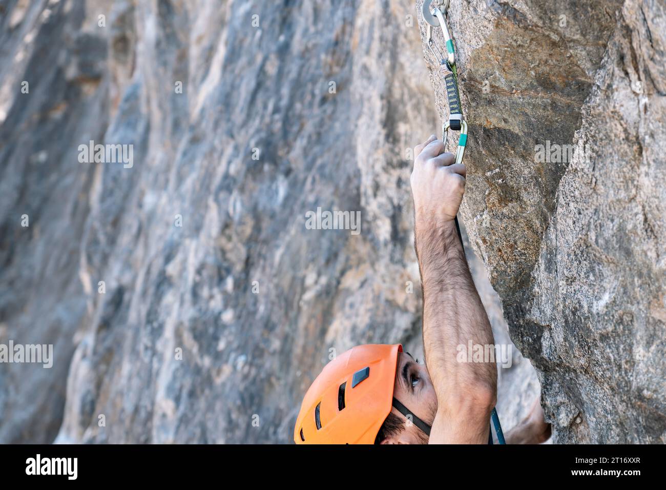 Primo piano dall'alto, arrampicata su roccia con imbracatura di sicurezza e casco per esterni. Foto Stock