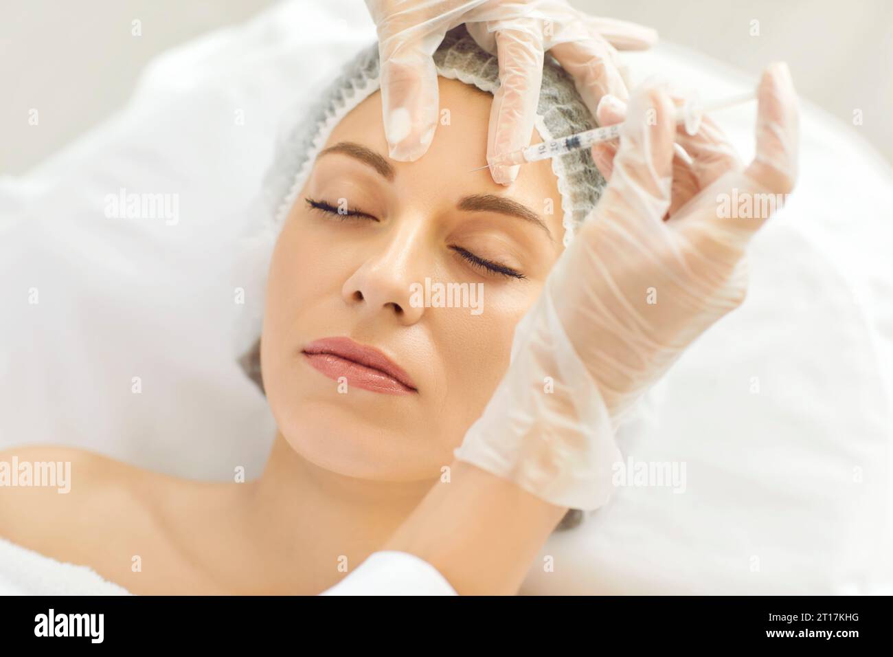 Cosmetologo effettua iniezioni ringiovanenti anti-rughe sul viso di bella donna. Foto Stock