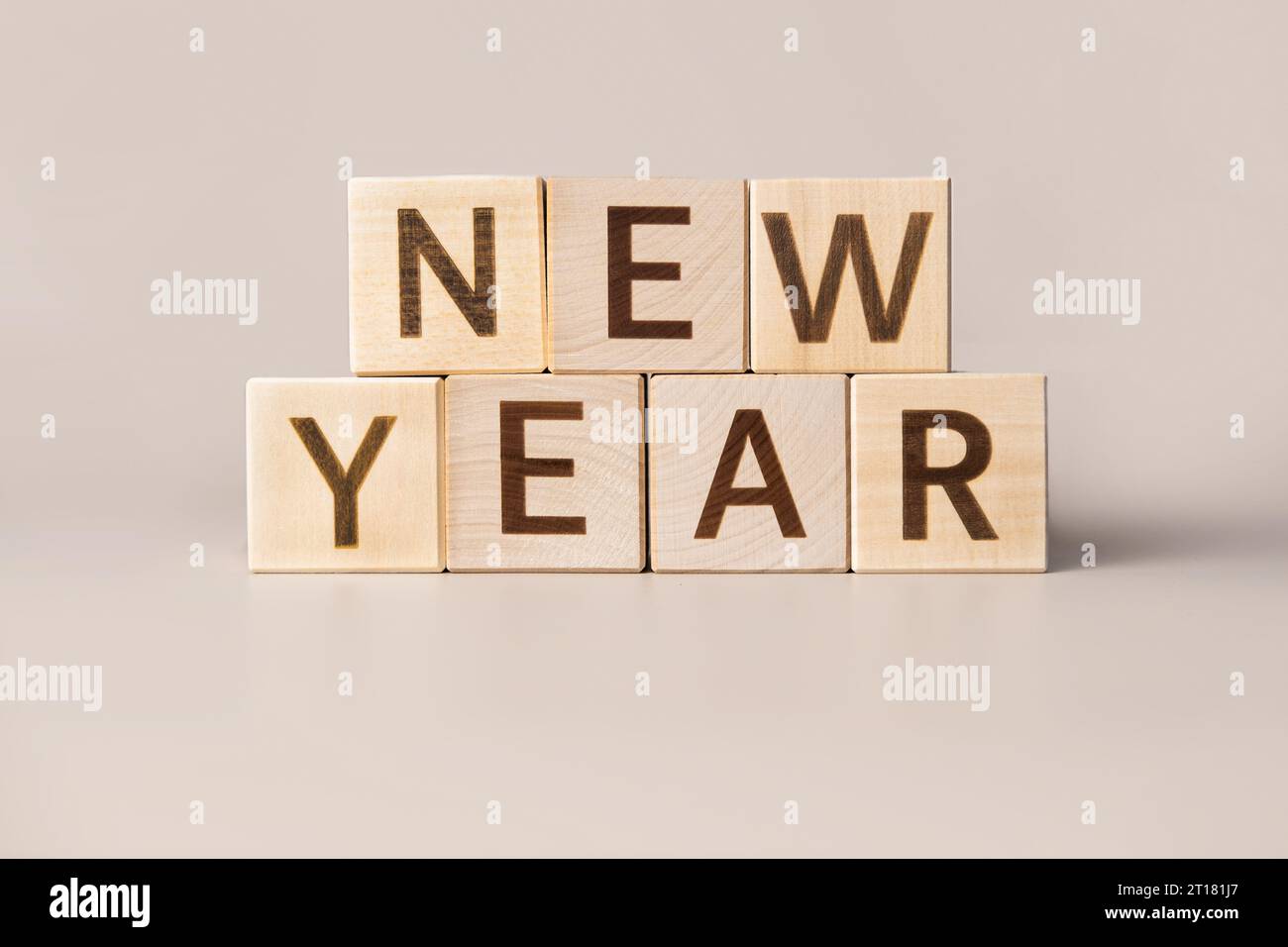 Il nuovo anno Word su cubi di legno su uno sfondo da studio neutro beige. Copia spazio. Scritto. Le parole contano. Decorazioni natalizie. Iscrizione Hap Foto Stock