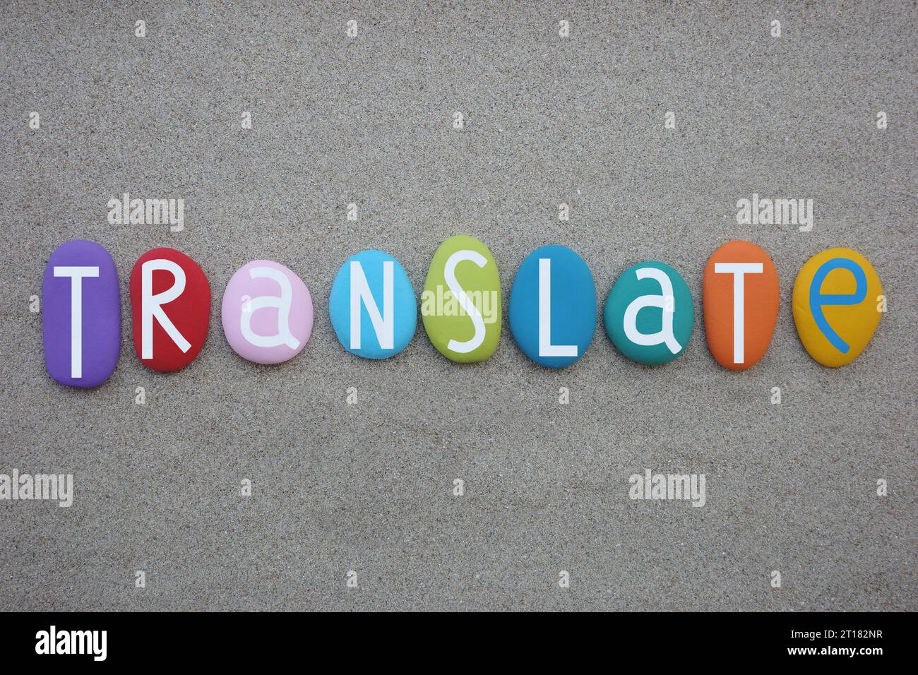 Traduce parole creative composte da lettere di pietra multicolore sulla sabbia della spiaggia Foto Stock