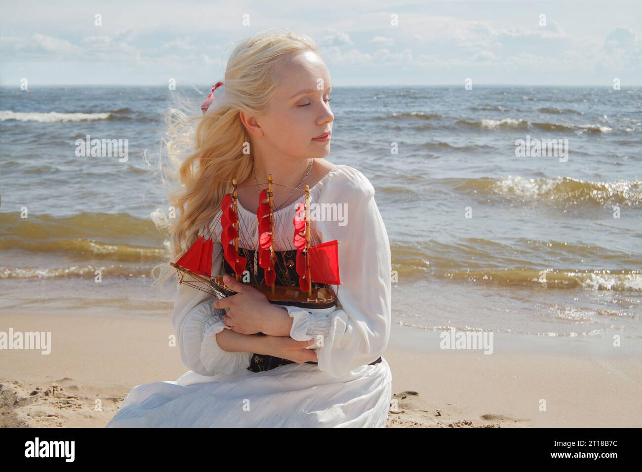 Vacanza romantica. Giovane donna con i capelli biondi seduta sulla spiaggia di mare, ritratto all'aperto Foto Stock