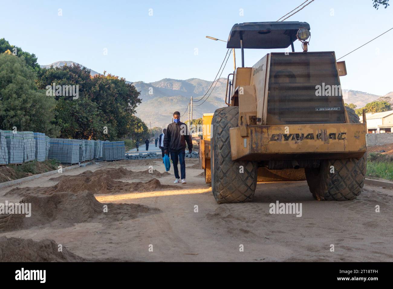 Pavimentatrici in calcestruzzo utilizzate per sostituire una strada sterrata Foto Stock