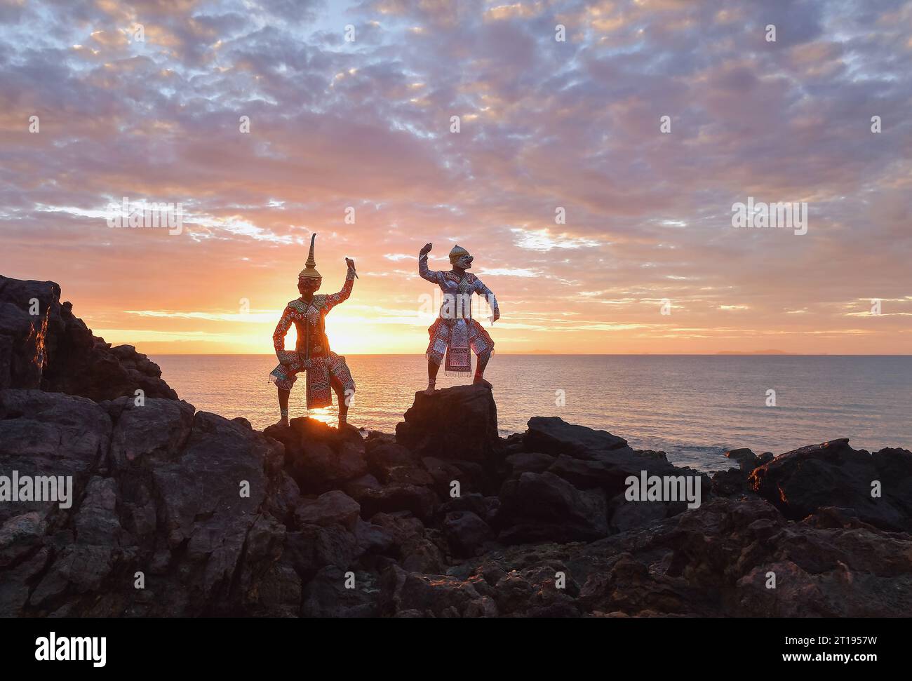 Due uomini che si esibiscono in danza tradizionale khon tailandese sulle rocce in riva al mare, Thailandia Foto Stock