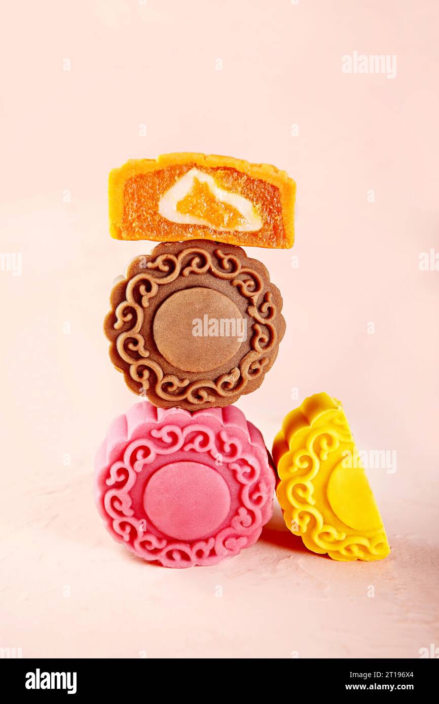 Disposizione di torte lunari multicolore assortite su sfondo rosa Foto Stock