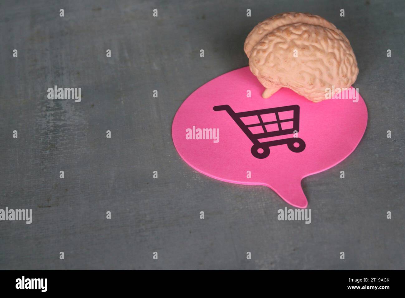 Un cervello umano e un fumetto con icona dei carrelli della spesa. Comportamento del consumatore, acquisto impulsivo e concetto di dipendenza dallo shopping. Foto Stock