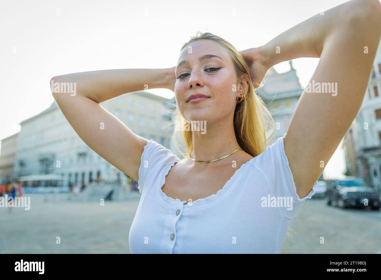 Una ragazza attraente tiene i capelli in piedi in centro in estate Foto Stock