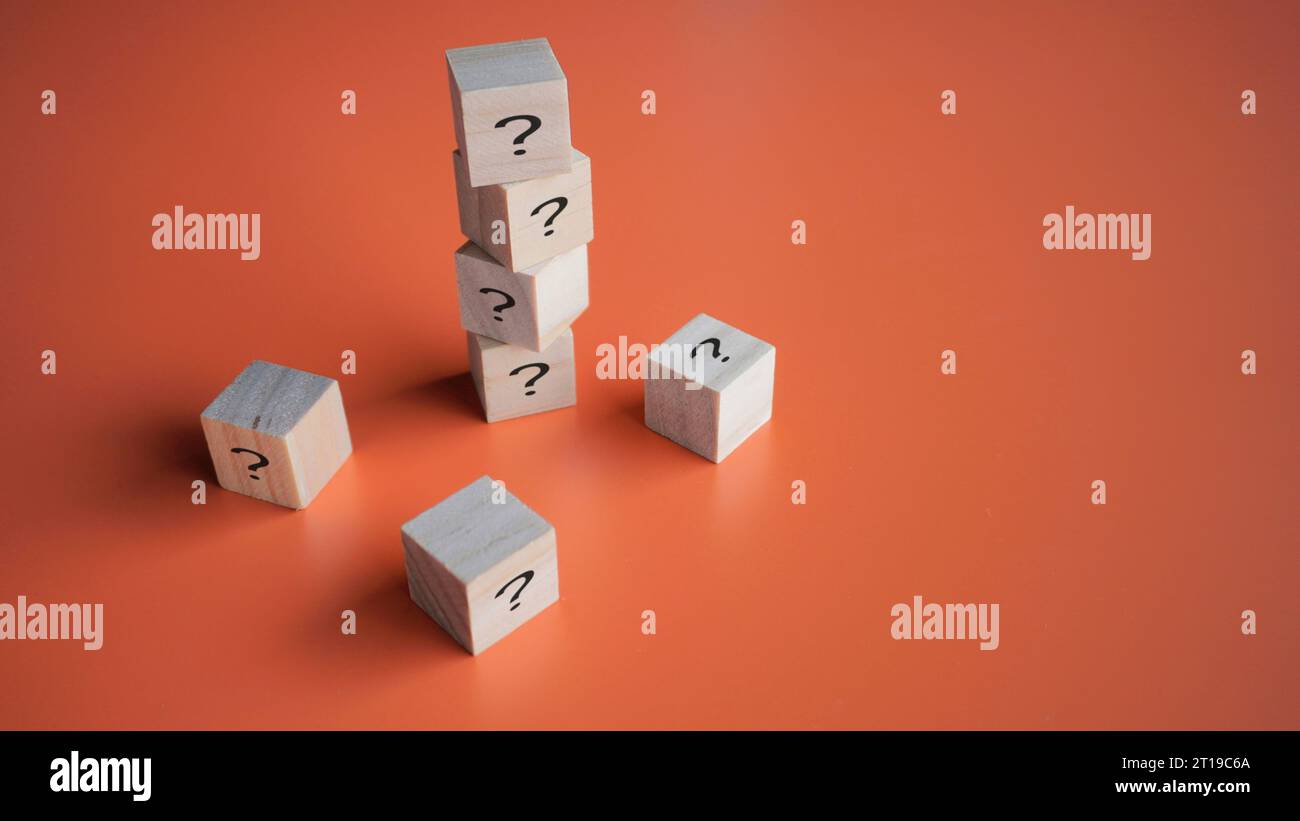 Una pila di blocchi di legno con l'icona dei punti interrogativi. Domande, curiosità, mistero, enigma e domande frequenti. Foto Stock