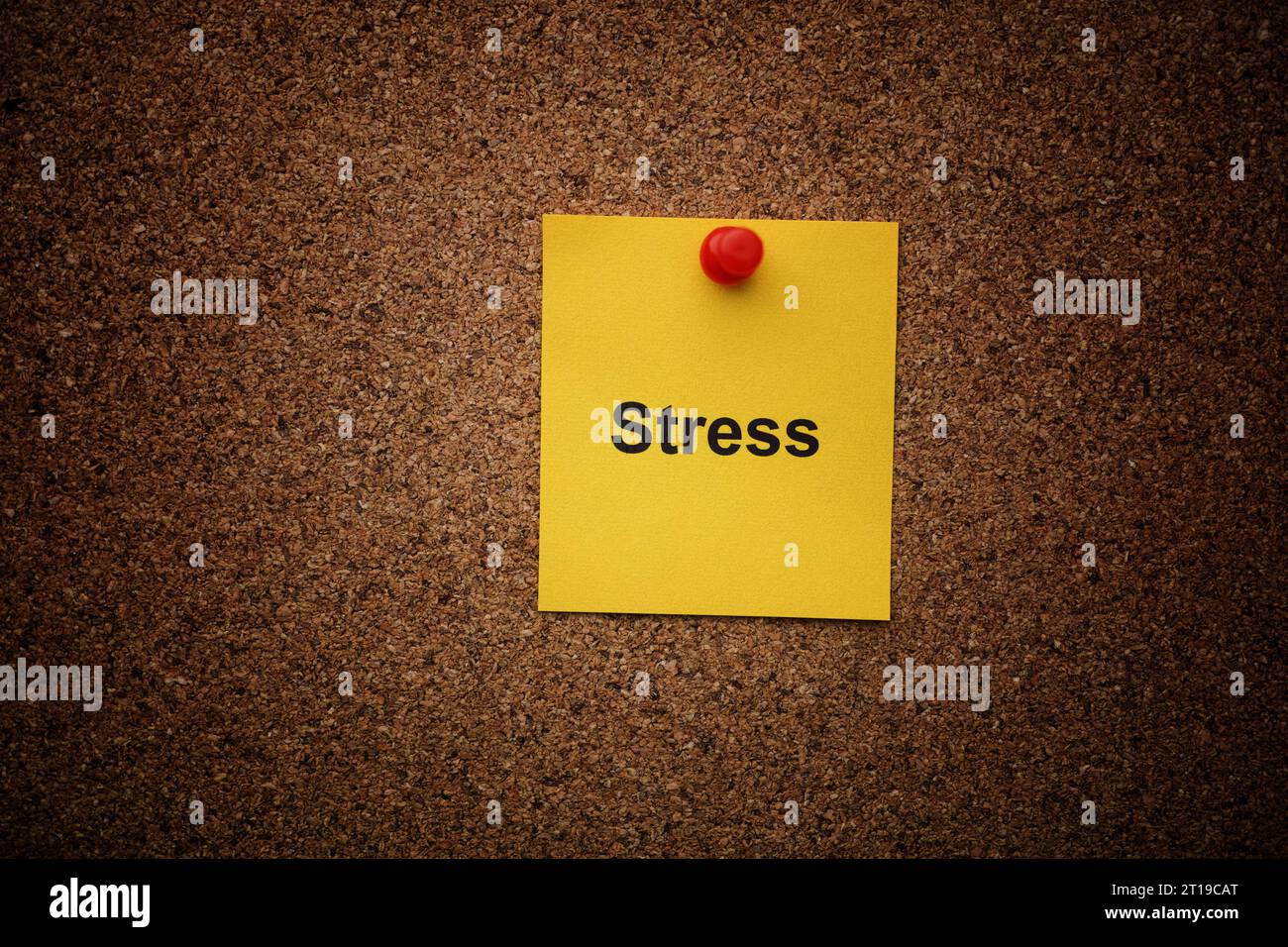 Una nota di carta gialla con la parola "stress" fissata su una tavola di sughero. Primo piano. Foto Stock