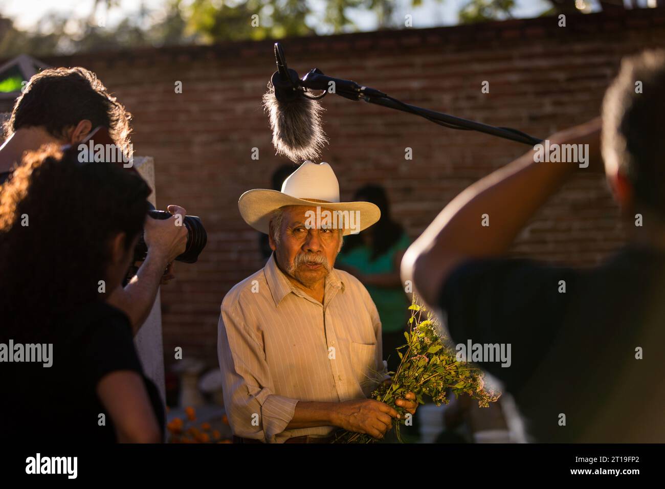 Una troupe di telecamere travolge un uomo anziano che mette fiori sulla tomba di sua moglie durante il festival Day of the Dead noto in spagnolo come Día de Muertos presso il vecchio cimitero, il 31 ottobre 2013 a Xoxocotlan, Oaxaca, Messico. Foto Stock