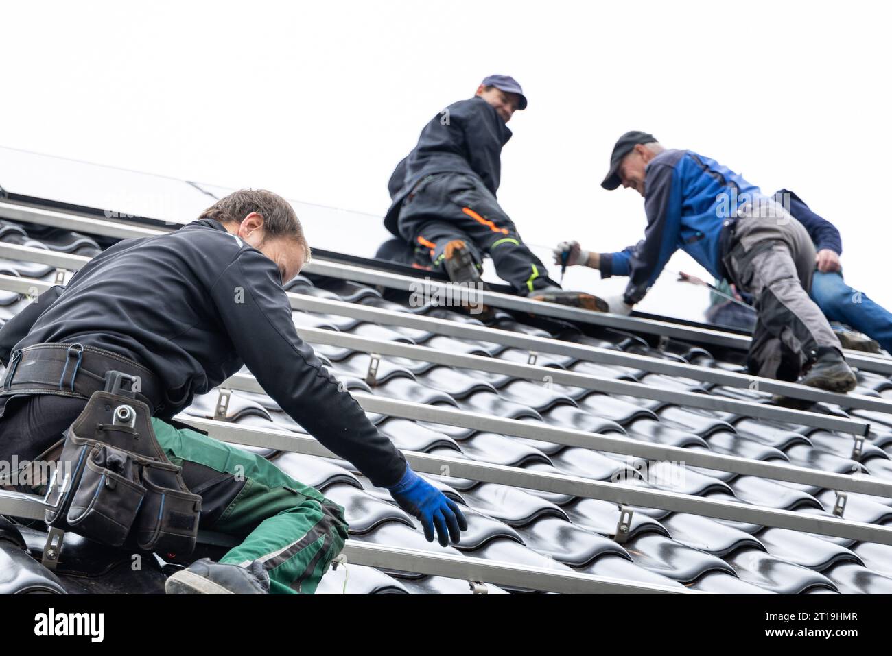 Tecnici soddisfatti sul tetto di una casa durante l'installazione di pannelli solari Foto Stock