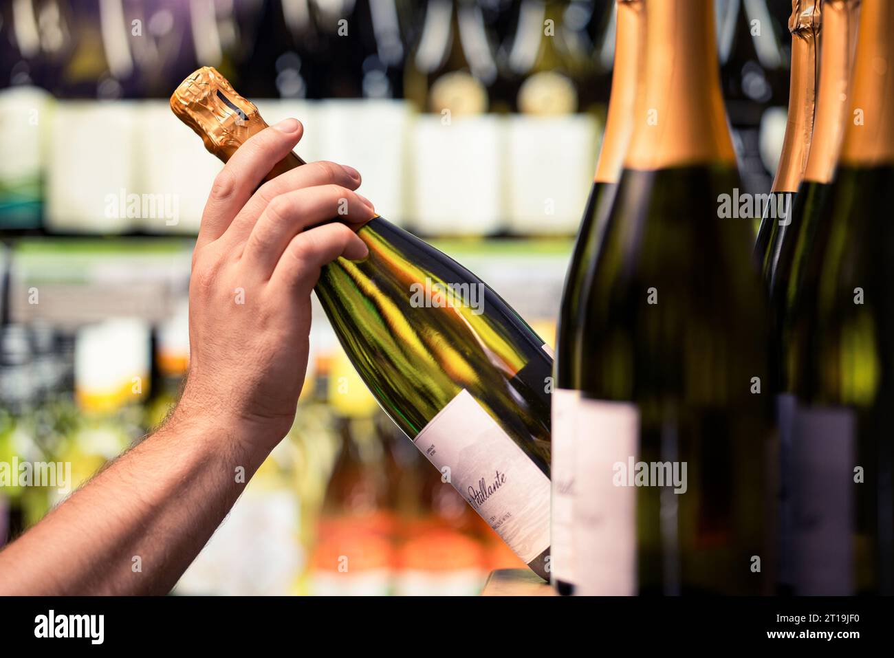 Vino frizzante da un negozio di alcolici. Bottiglia in mano. Negozio di liquori. Esposizione di prosecco o champagne al mercato degli alcolici o al supermercato. Foto Stock