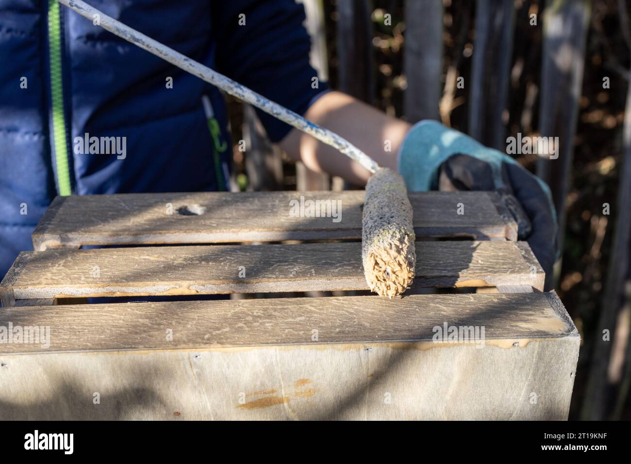 un bambino dipinge una scatola di legno con pennelli in giardino Foto Stock