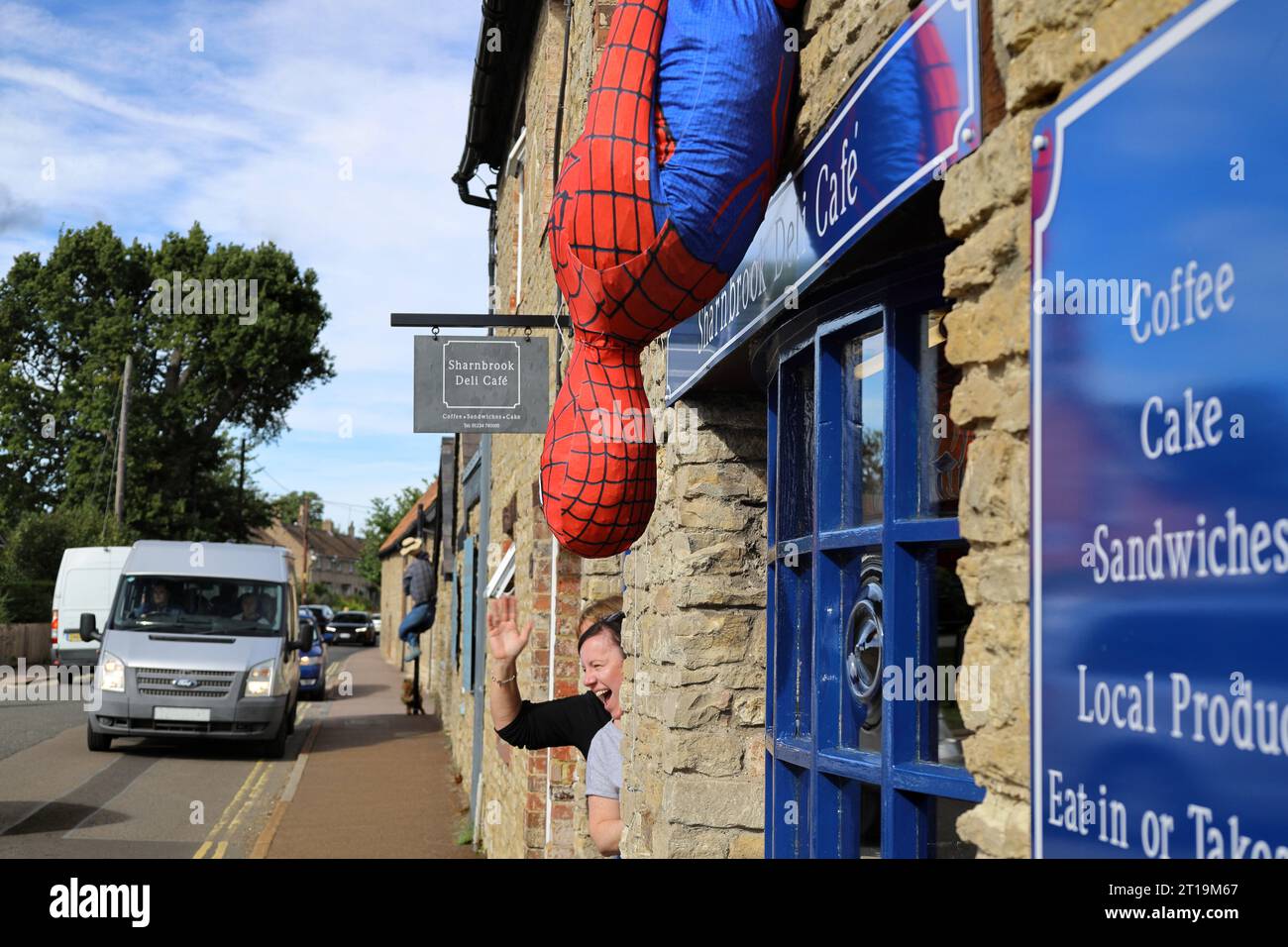 Lo spaventapasseri Spider-man fuori dal Deli Cafe durante il festival dello spaventapasseri del villaggio a Sharnbrook High Street, Bedfordshire, Inghilterra, Regno Unito Foto Stock