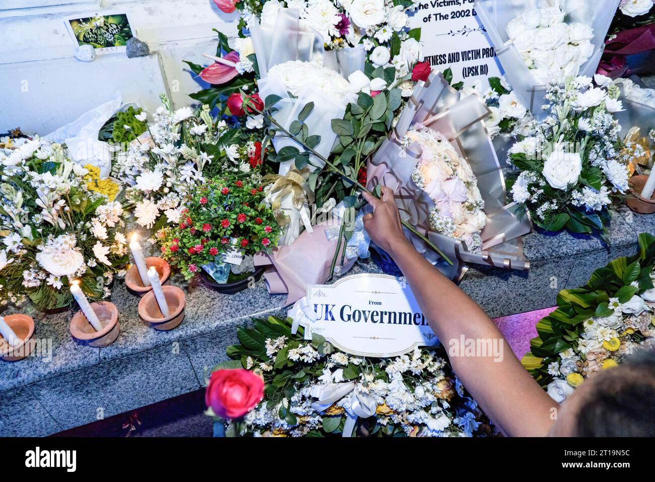 Badung, Indonesia. 12 ottobre 2023. Una donna mette fiori in una veglia per le vittime al Gorund Zero Memorial. Bali per commemorare il ventunesimo anniversario dell'esplosione consecutiva nota come bombardamento di Bali, che ha ucciso 202 persone di molte nazionalità nell'area di Legian. Credito: SOPA Images Limited/Alamy Live News Foto Stock