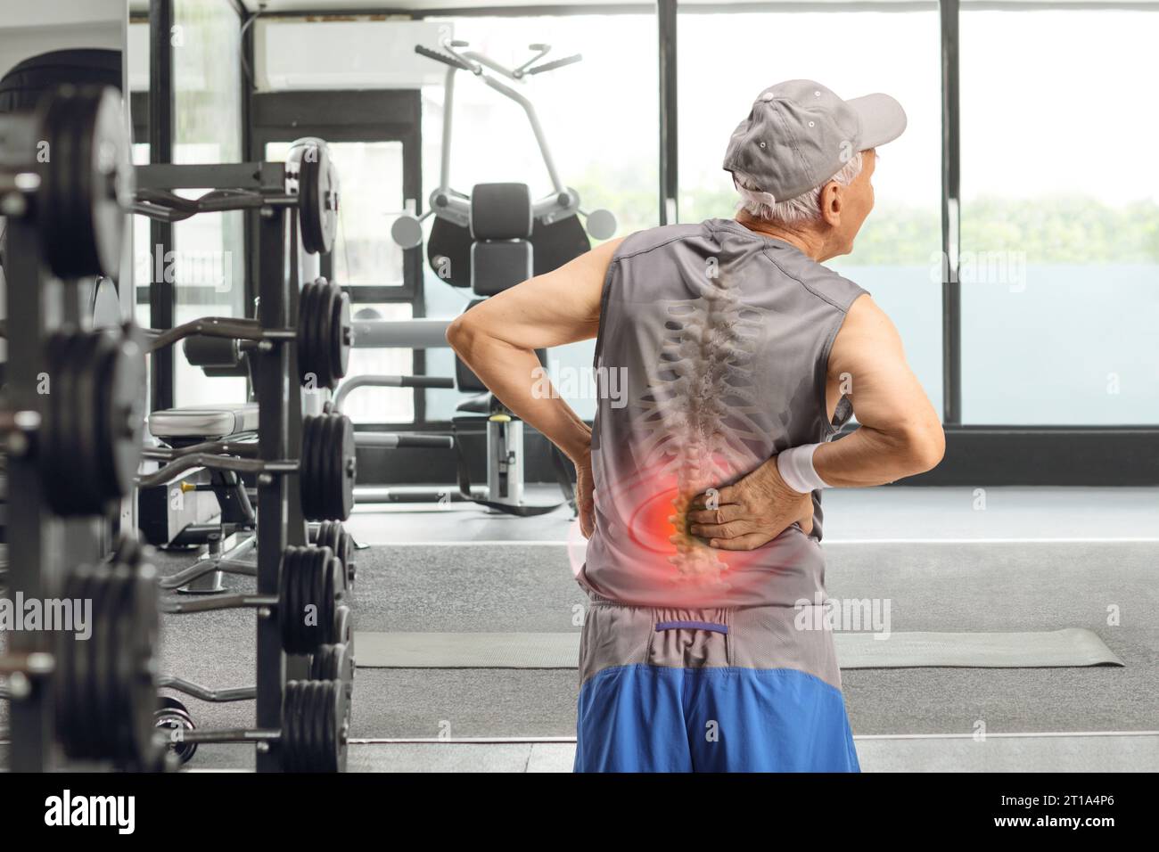 Foto retrovisiva di un uomo anziano che si tiene la schiena con osso colonna vertebrale visibile in una palestra Foto Stock