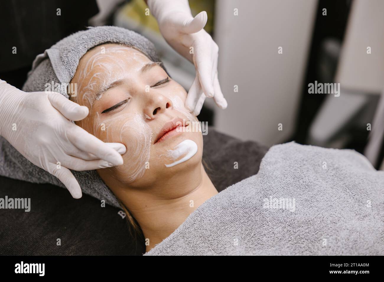 Massaggio viso donna trattamento viso pelle con essenza naturale estratto di erbe crema idratante in beauty spa. Foto Stock