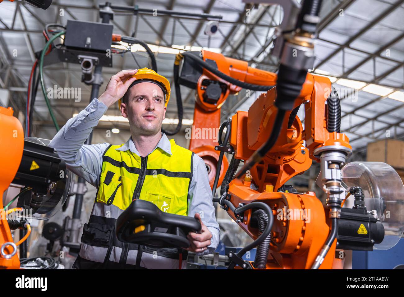 Uomo ingegnere moderno intelligente che utilizza la moderna tecnologia robotica. Configurazione del braccio di saldatura robotizzato nel processo di produzione dell'automazione in fabbrica Foto Stock