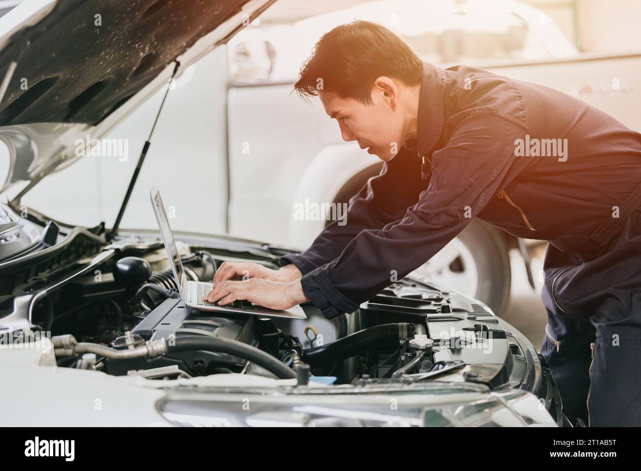 meccanico professionale, lavoro maschile, sintonizzazione della fasatura di accensione del motore in ecu con computer portatile in officina officina per auto da corsa Foto Stock
