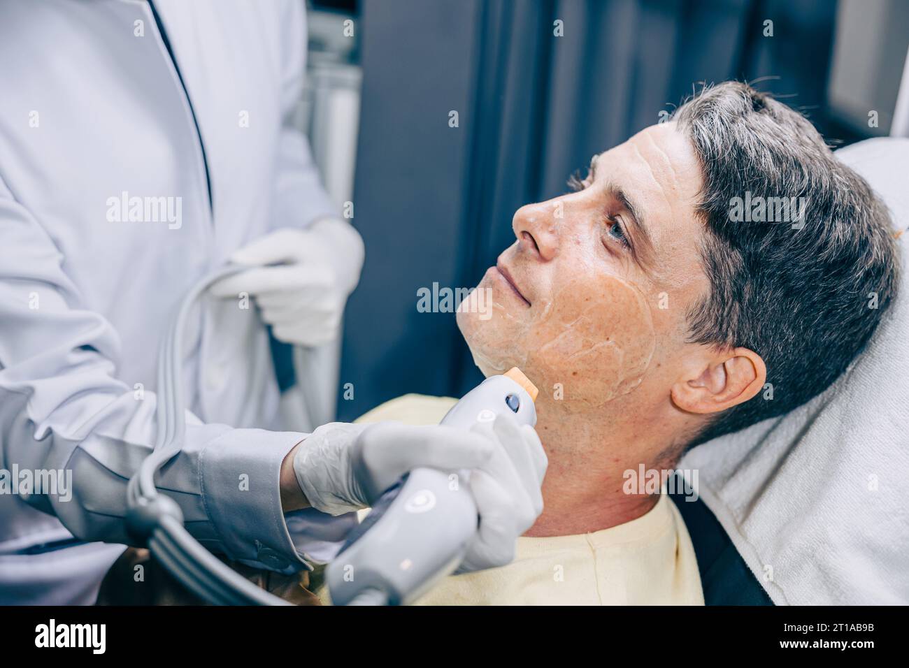 Medico della pelle che utilizza la tecnologia di trattamento viso viso con trattamento laser risurfacing con maschio adulto per ridurre rughe e cicatrici presso la clinica anti invecchiamento Foto Stock