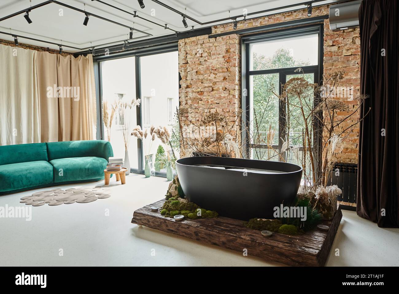 vasca da bagno nera all'interno del moderno appartamento con divano in velluto blu, finestre panoramiche e piante Foto Stock