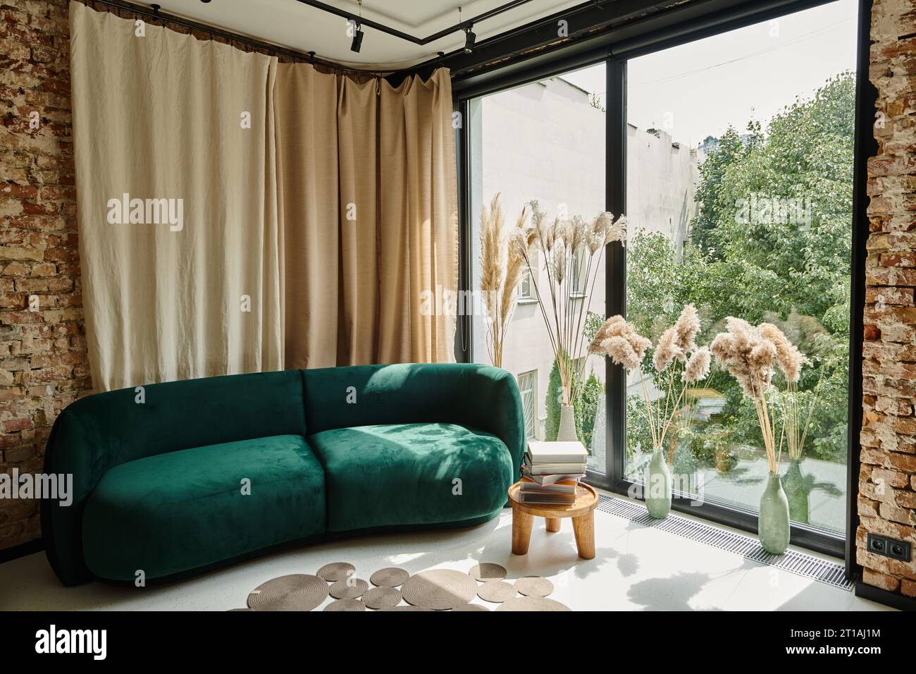 appartamento moderno con divano in velluto blu, libri su tavolino e finestre panoramiche, contemporaneo Foto Stock