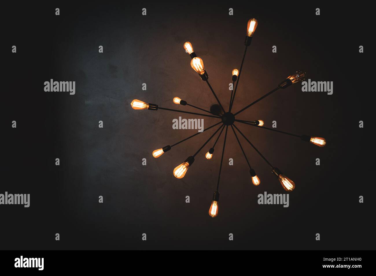 Un lampadario decorativo nero sputnik d'epoca appeso a un soffitto scuro in una stanza Foto Stock