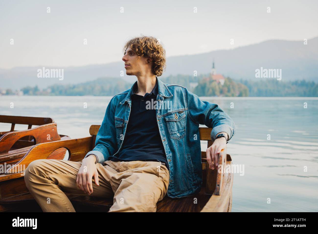 Un uomo si rilassa seduto su una barca nel lago e guarda intorno Foto Stock