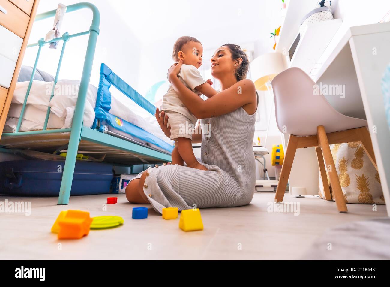 Giovane madre caucasica che gioca con lei nella stanza con i giocattoli. Bambino da meno di un anno che impara le prime lezioni di sua madre. Madre che gioca con Foto Stock