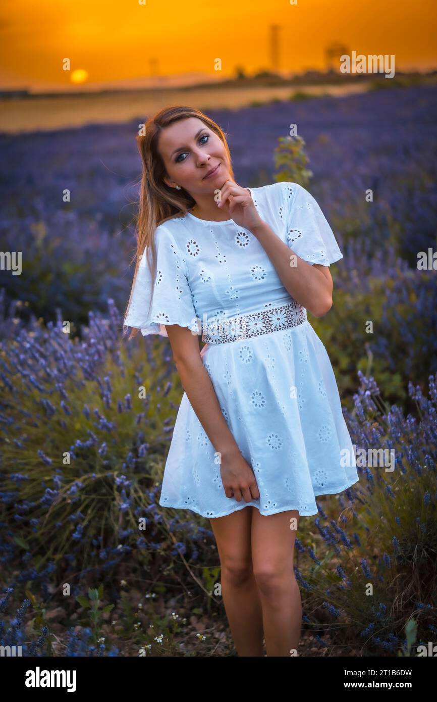 Una giovane donna bionda caucasica con un vestito bianco in un campo di lavanda coltivato a Navarra, in Spagna. stile di vita, stile di vita rurale in viola lavanda Foto Stock