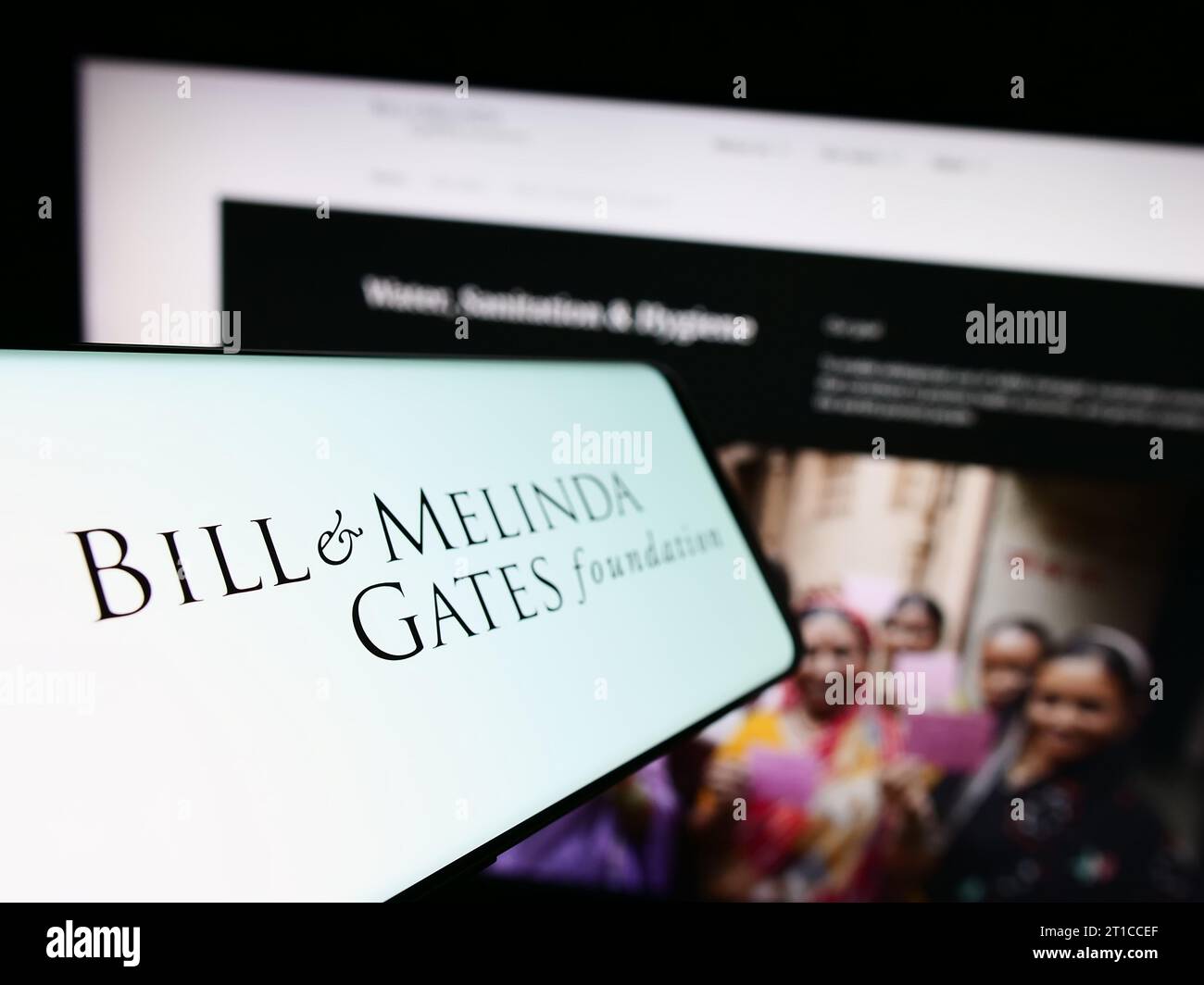 Smartphone con logo di American Bill e Melinda Gates Foundation (BMGF) davanti al sito web. Mettere a fuoco il display centrale sinistro del telefono. Foto Stock