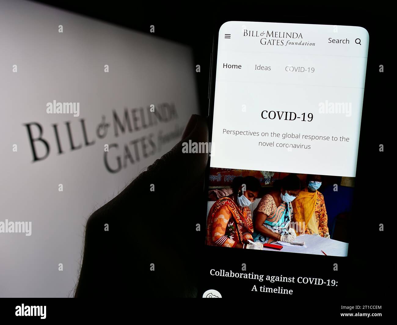 Persona in possesso di cellulare con sito web dell'American Bill and Melinda Gates Foundation (BMGF) davanti al logo. Concentrarsi sul centro del display del telefono. Foto Stock