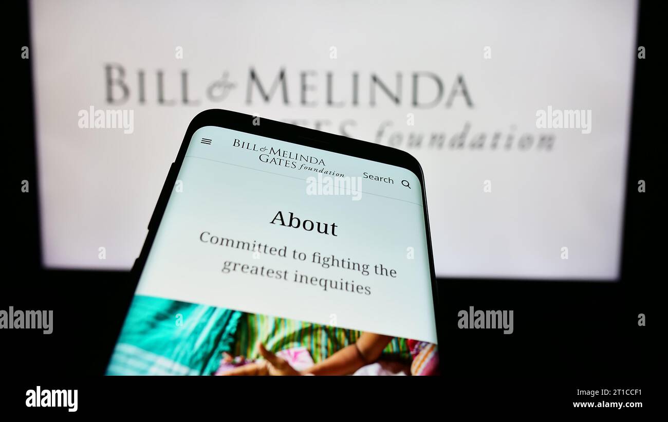 Telefono cellulare con pagina web dell'American Bill and Melinda Gates Foundation (BMGF) davanti al logo. Mettere a fuoco in alto a sinistra sul display del telefono. Foto Stock