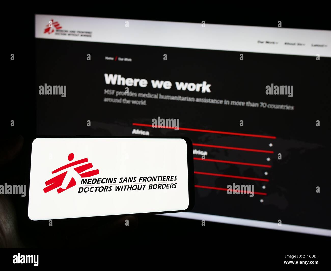 Persona che detiene il cellulare con il logo dell'organizzazione benefica Medici senza frontiere davanti alla pagina web. Concentrarsi sul display del telefono. Foto Stock
