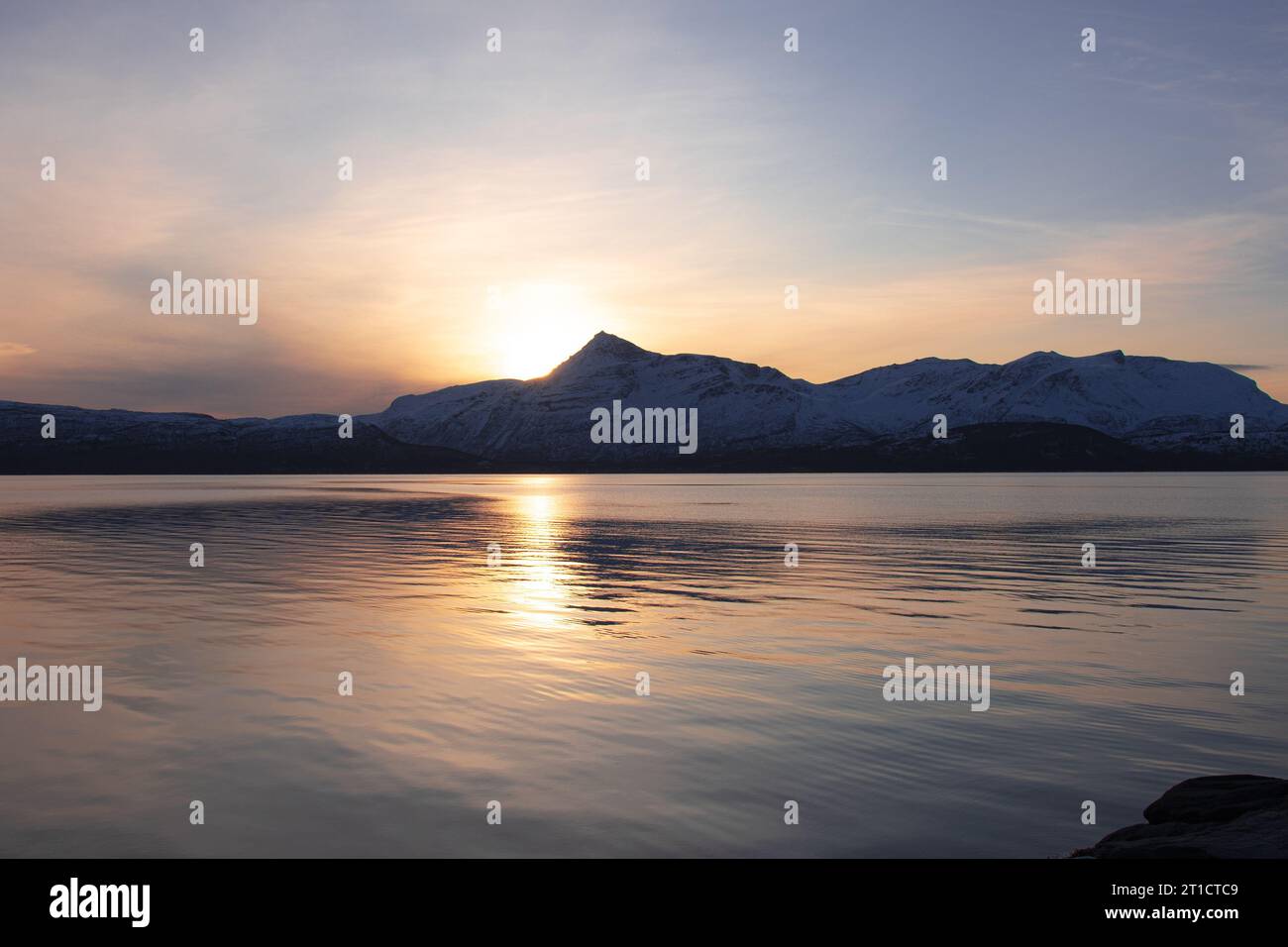 Il sole tramonta dietro le montagne norvegesi Foto Stock