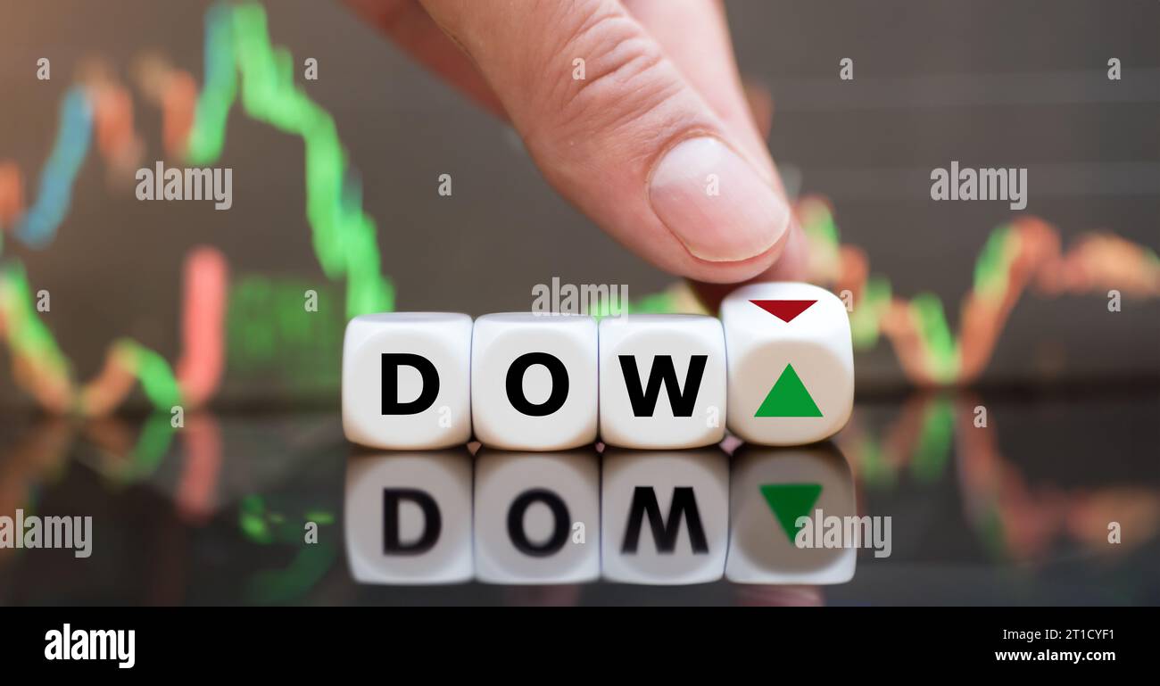 Simbolo di un trend variabile dell'indice Dow Jones. Mano gira i dadi e cambia l'orientamento di una freccia accanto alla parola Dow. Foto Stock