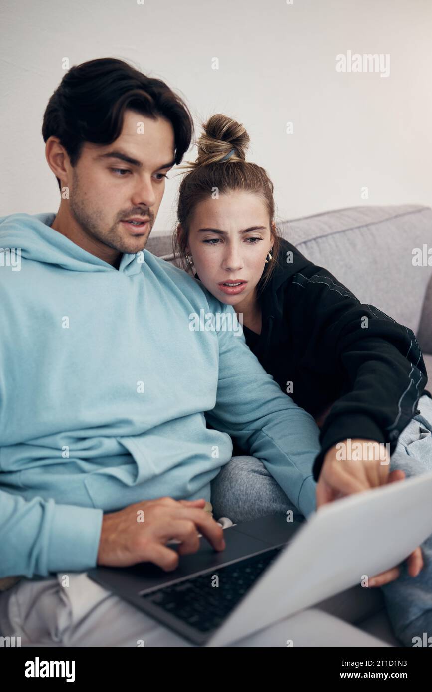 Laptop, stress e coppia che puntano nel salotto di casa per pianificare il budget, le tasse o il debito. Computer, uomo e donna frustrata sul divano per la finanza Foto Stock