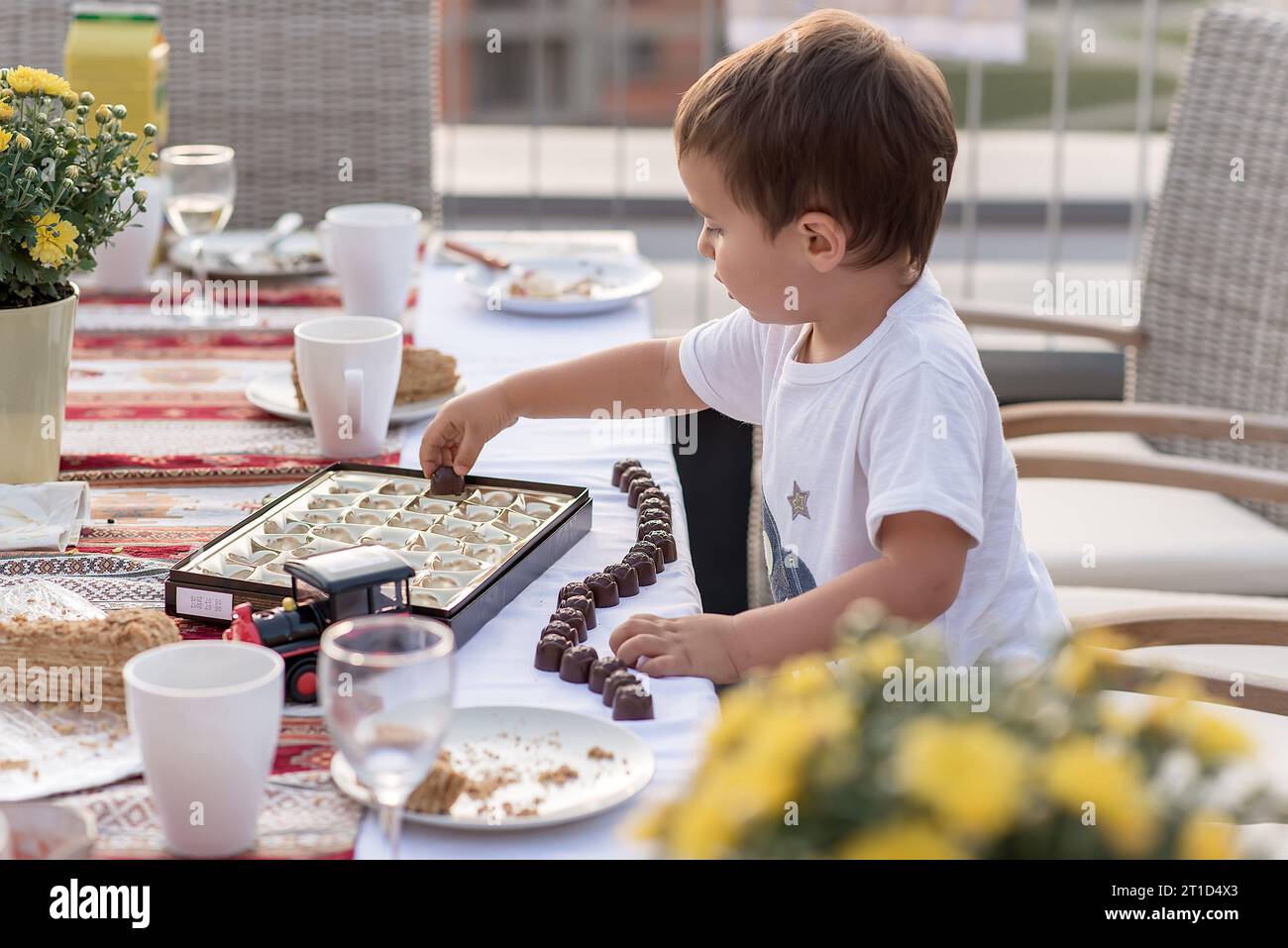 Un bambino carino che gioca con caramelle di cioccolato sulla terrazza Foto Stock