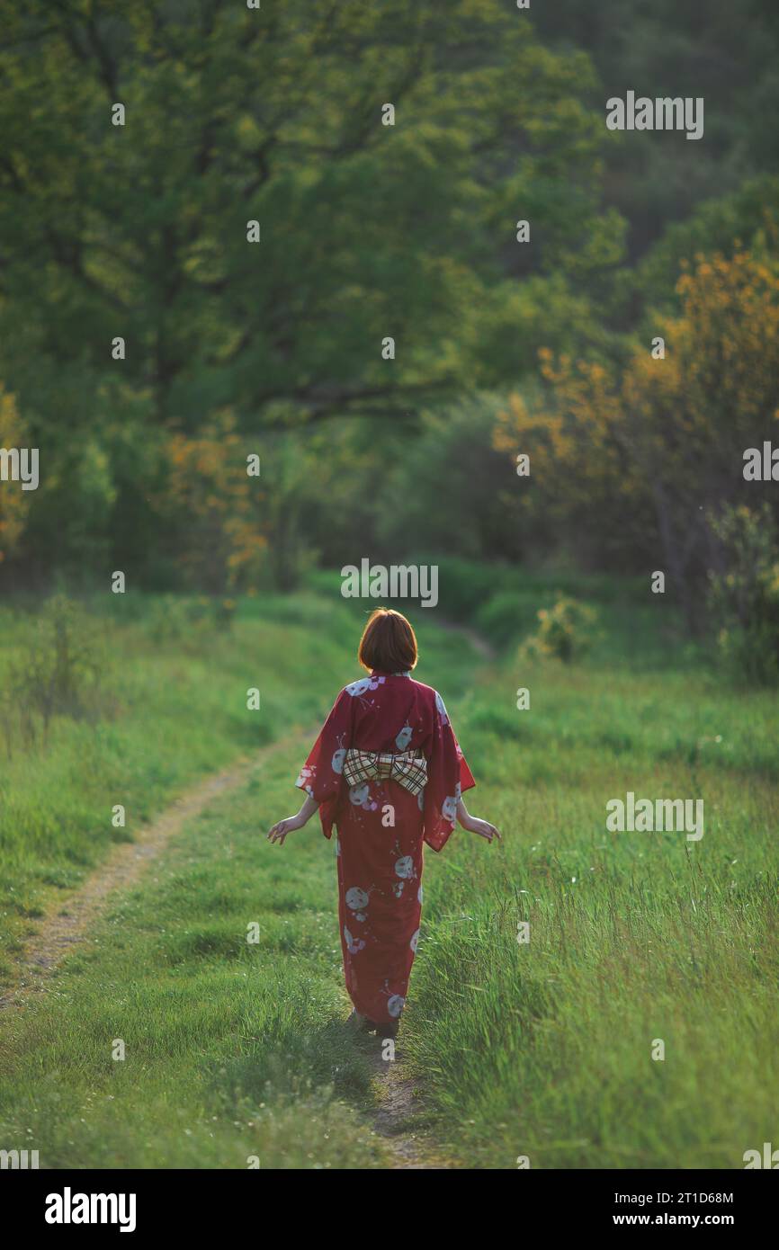 donna in kimono rosso che cammina all'aperto Foto Stock
