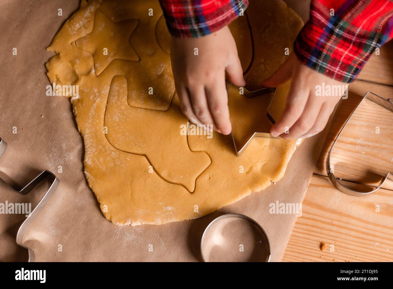 Primo piano delle mani di un bambino che distribuisce la pasta per biscotti per Natale. Foto di alta qualità Foto Stock