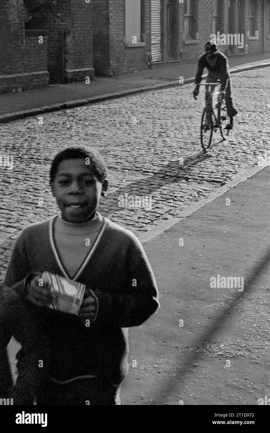 Ragazzi in una Sanderson Street acciottolata di ritorno da una commissione per lo shopping durante la slum di Victorian St Ann's, Nottingham. 1969-1972 Foto Stock