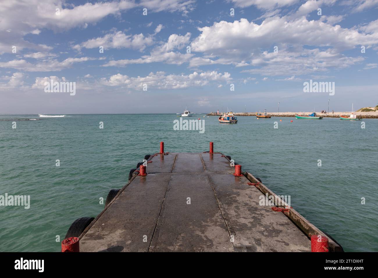 Una scenografia pittoresca si svolge con le colorate barche da pesca ormeggiate serenamente al sole radioso di un porto tranquillo Foto Stock