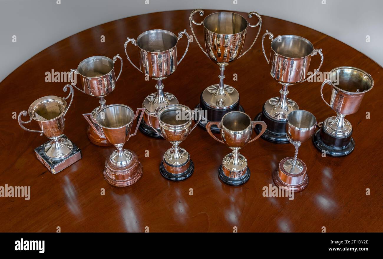 Esposizione di trofei e coppe in argento incisi su un tavolo rotondo in legno di mogano Foto Stock
