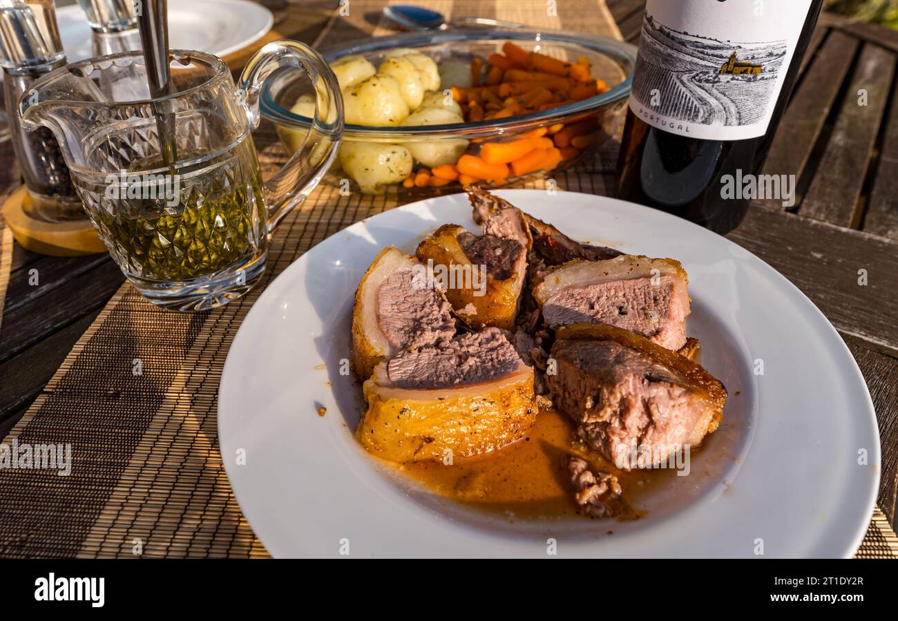 Piatto con agnello con salsa alla menta, patate e carote, bottiglia di vino Foto Stock