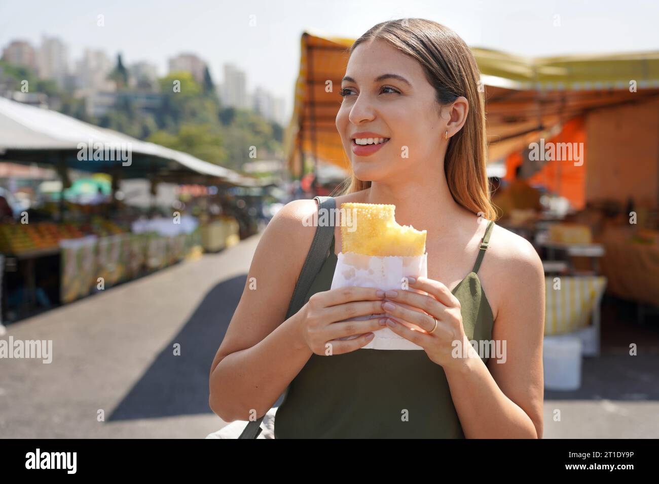 Primo piano di una bella ragazza che mangia il tradizionale pastel de Feira brasiliano a San Paolo, Brasile Foto Stock