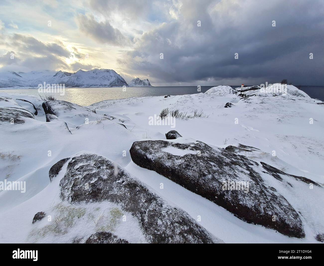 Lastre di roccia innevate sul promontorio con nuvole di maltempo, Senja, Troms og Finnmark, Norvegia Foto Stock
