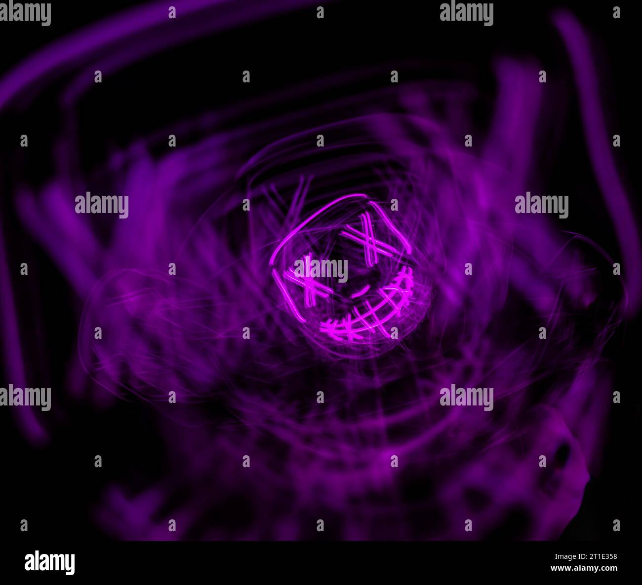 Persona al neon viola, illumina la maschera di halloween. Foto Stock