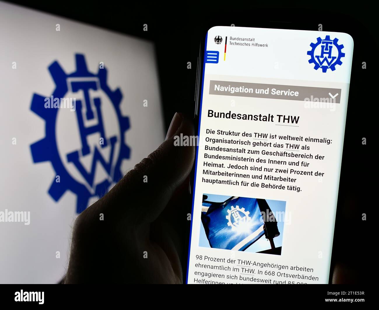 Persona in possesso di cellulare con sito web dell'organizzazione Bundesanstalt Technisches Hilfswerk (THW) davanti al logo. Concentrarsi sul centro del display del telefono. Foto Stock
