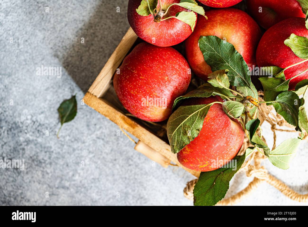 Scatola di legno con mele rosse su tavolo in cemento Foto Stock